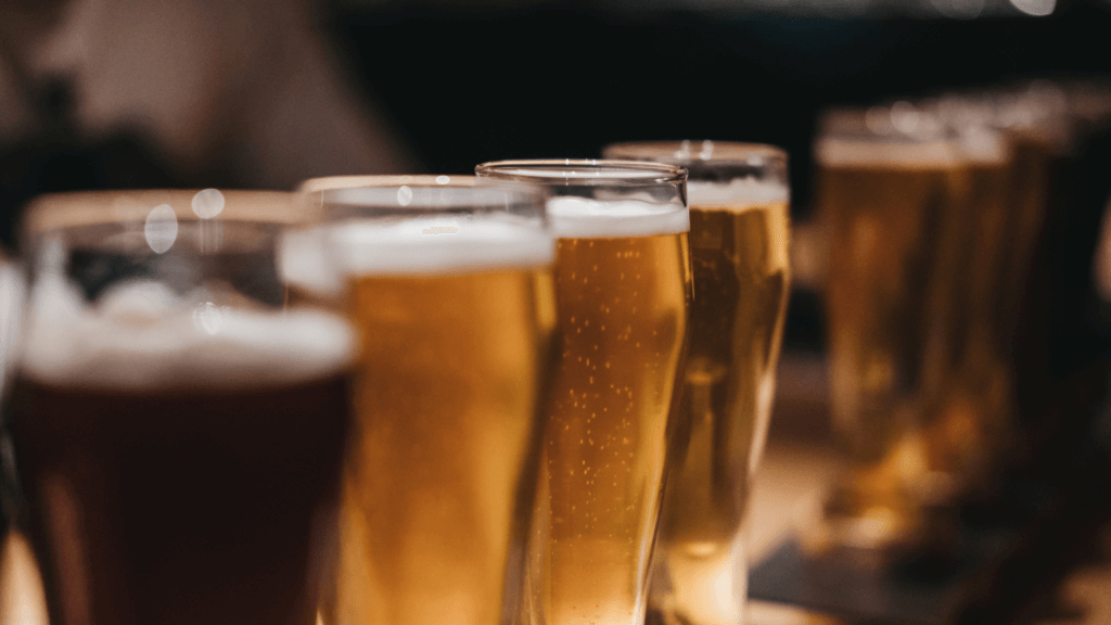 Glasses full of amber-colored liquid are lined up.